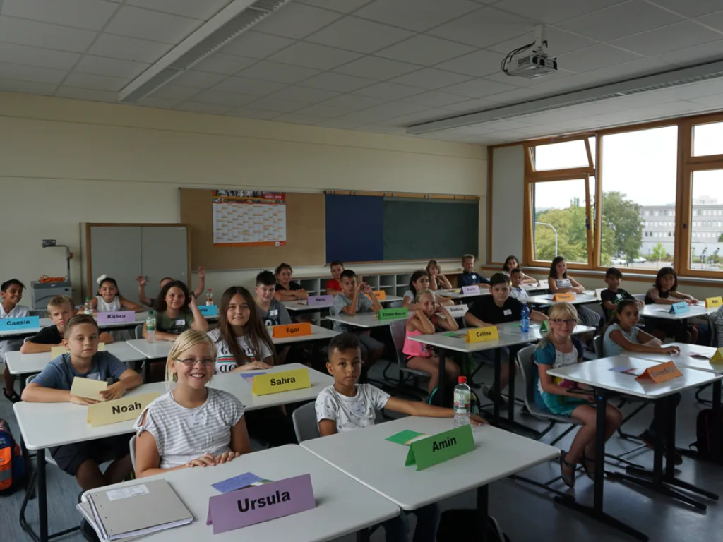 Kinder blicken von ihren Plätzen zur Kamera.